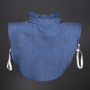 K&ouml;nnte beinhalten: Ein Denim-Kragen mit R&uuml;schenkante und wei&szlig;en B&auml;ndern. Der Kragen ist hellblau und aus einem weichen, bequemen Stoff gefertigt.