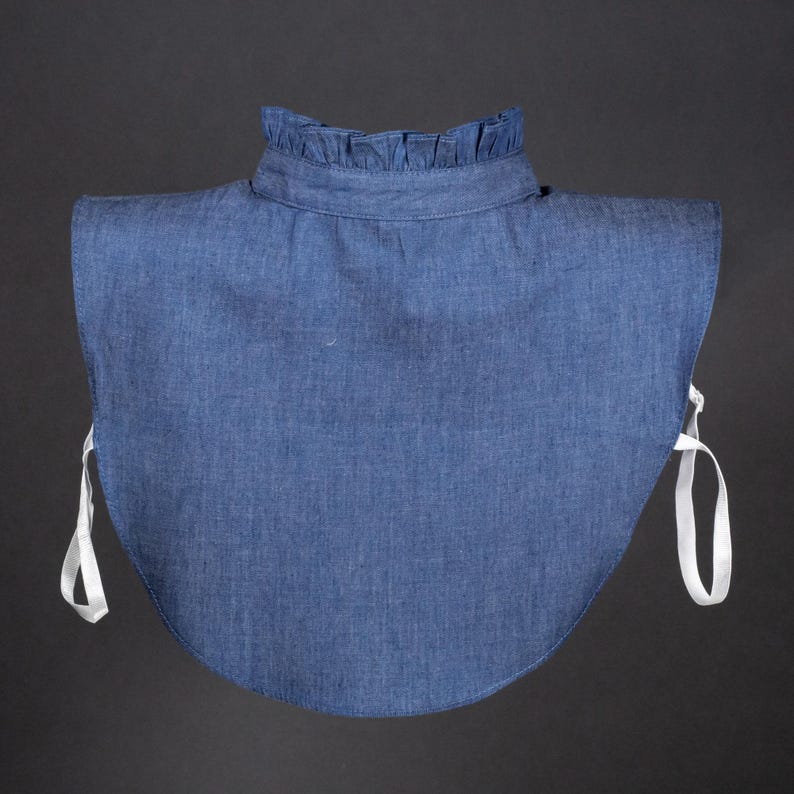 K&ouml;nnte beinhalten: Ein Denim-Kragen mit R&uuml;schenkante und wei&szlig;en B&auml;ndern. Der Kragen ist hellblau und aus einem weichen, bequemen Stoff gefertigt.