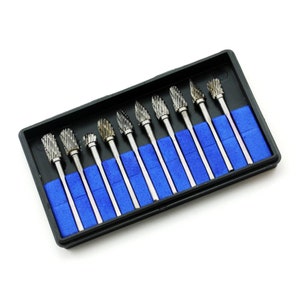 May include: A set of ten silver rotary burr bits presented in a black plastic case with blue foam inserts. The burrs have different head shapes and are designed for use with rotary tools.
