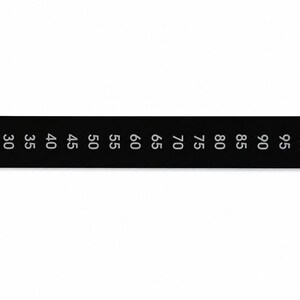 May include: A rectangular black temperature strip featuring white printed numbers ranging from 25 to 100, followed by the symbol &deg;C. The strip is designed for monitoring heat levels and displays clear, evenly spaced numerical increments for reading.