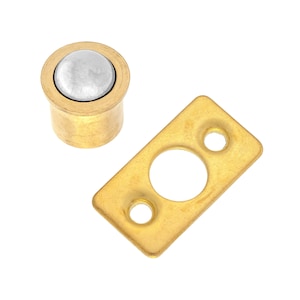 May include: A brass door catch with a round, silver-colored ball bearing. The catch is designed to hold a door open.