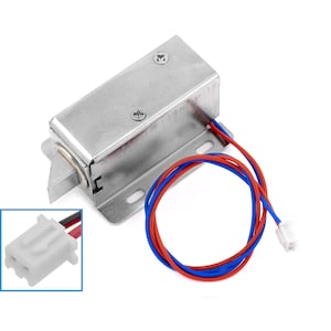May include: A silver electric door lock with a red and blue wire connector. The lock has a metal latch and a rectangular shape.