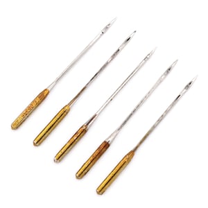May include: Five silver sewing needles with gold colored tips. The needles are arranged in a row on a white background.