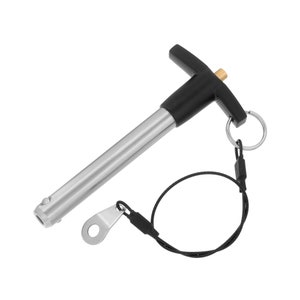 May include: A silver and black pin with a T-shaped handle and a black cord attached. The pin has a small ring on the end of the cord.