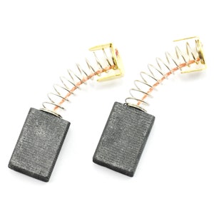 Könnte beinhalten: Zwei Kohlebürsten für Elektrowerkzeuge. Jede Bürste hat einen rechteckigen Graphitblock, eine Spiralfeder und einen goldfarbenen Metallverbinder. Die Komponenten sind auf weißem Hintergrund angeordnet.