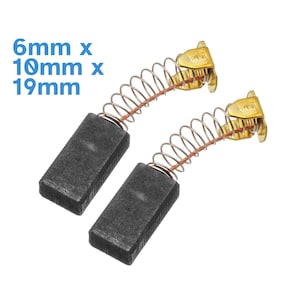 Könnte beinhalten: Zwei schwarze Kohlebürsten mit goldfarbenen federbelasteten Anschlüssen. Die Bürsten sind 6 mm x 10 mm x 19 mm groß.