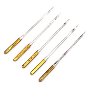 May include: Five silver sewing machine needles with gold colored tips. The needles are labeled "SCHMETZ 130/705" and "ORGAN 70/10".