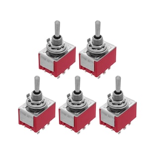 Peut inclure: Cinq interrupteurs à bascule argentés avec des bases en plastique rouge. Les interrupteurs sont en position d'arrêt.