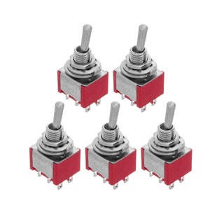 Peut inclure: Cinq interrupteurs à bascule argentés avec des bases en plastique rouge. Les interrupteurs sont en position d'arrêt.