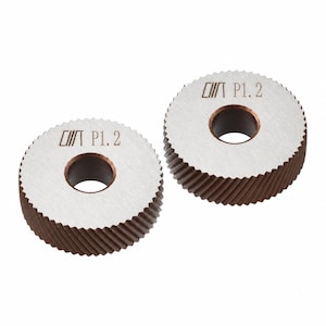 May include: Two circular metal gears with a silver-toned flat top surface and dark brown, angled teeth along the outer edge. Each gear features a central circular hole and is engraved with the text "/// P1.2" on the top face.