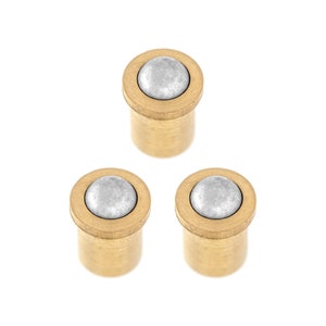 May include: Three gold-coloured door stops with a silver ball on top. Each door stop has a round base and a cylindrical body.