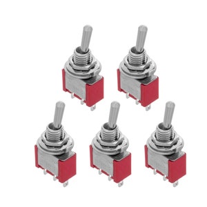 Op de afbeelding: Vijf zilveren schakelaars met rode kunststof bases. De schakelaars staan in de ON-positie.