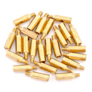 May include: A collection of small, gold-coloured standoffs with threaded ends. These hexagonal standoffs are arranged on a white surface, showcasing their metallic sheen and uniform design. They are likely used for electronics or hardware applications.