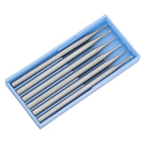 May include: A set of six silver-colored drill bits in a blue plastic case. The drill bits are arranged in a row, with the tips facing the viewer.