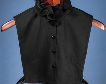 May include: A black faux collar with a ruffled neckline and button closure. The collar is made of a soft, lightweight fabric and is perfect for adding a touch of elegance to any outfit.