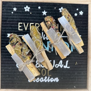 May include: Four bundles of Palo Santo sticks tied with twine and wrapped around a clear crystal. The bundles are arranged on a black background with the text "EVERYTHING IS CONNECTION & ALL creation" visible.