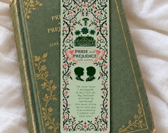 Könnte beinhalten: Ein rechteckiges Lesezeichen mit hellgrünem Hintergrund, schwarzen Blumenranken, rosa Blüten, einer grünen Hausillustration und den Silhouetten zweier Personen. Es zeigt den Text Pride and Prejudice von Jane Austen sowie ein Zitat.