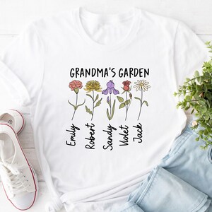 May include: White t-shirt with the text "Grandma's Garden" and five flowers with names below each flower: Emily, Robert, Sandy, Violet, Jack.