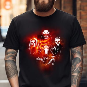May include: A black t-shirt featuring a white graphic of five Star Wars villains against a fiery orange and red background. The villains are Darth Vader, Kylo Ren, Darth Maul, and two others.