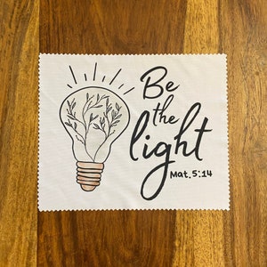 May include: White square cloth with a light bulb design and the text "Be the light Mat. 5:14".