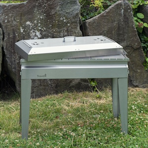 May include: A silver portable grill with a lid open on a stand. The grill has the word 