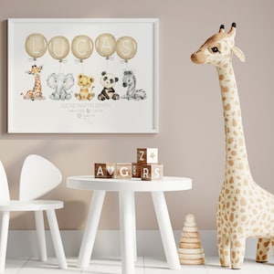 May include: A framed nursery print featuring the name "LUCAS" in gold balloons, with watercolor animal illustrations below. A giraffe, elephant, lion, panda, and zebra are depicted. The print includes the baby's name, birthdate, and time. A wooden giraffe and children's furniture are also in the image.