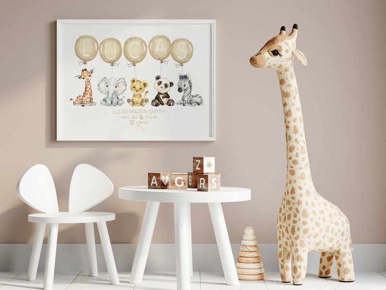 May include: A framed nursery print featuring the name "LUCAS" in gold balloons, with watercolor animal illustrations below. A giraffe, elephant, lion, panda, and zebra are depicted. The print includes the baby's name, birthdate, and time. A wooden giraffe and children's furniture are also in the image.
