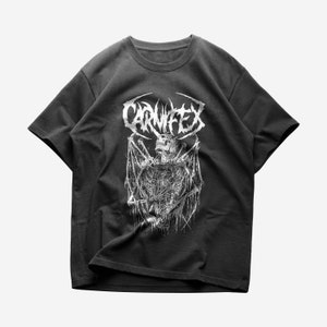 May include: A black t-shirt with a white graphic print of a skeleton with wings and the word "CARNIFEX" in a stylized font.