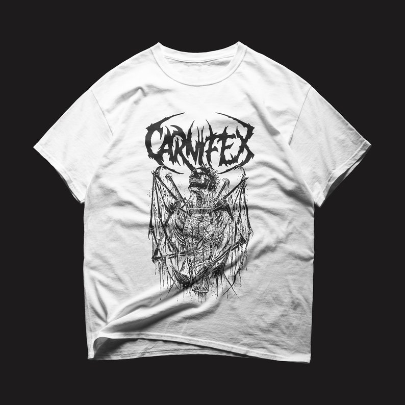 May include: White t-shirt with a black and white graphic print of a skull with wings and the word "CARNIFEX" above it.