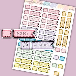 May include: A sheet of colourful planner stickers with days of the week and the number 23. The stickers are in various colours, including pink, blue, yellow, and green. The stickers are designed with a dashed line border and a banner shape.