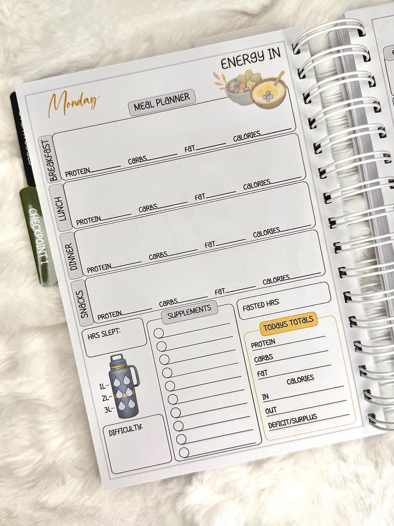 May include: A spiral-bound meal planner open to a Monday page. The page includes sections for breakfast, lunch, dinner, and snacks, with spaces for protein, carbs, fat, and calories. A water bottle graphic is on the bottom left.