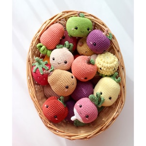 May include: A wicker basket filled with crocheted fruit and vegetable toys. The toys are in various colors, including red, green, yellow, orange, and purple. Each toy has a cute, embroidered face.