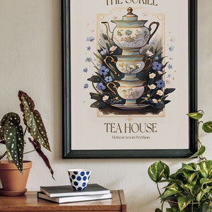 May include: A black framed poster with a vintage illustration of a tea set with a teapot and three cups stacked on top of each other. The poster has the text "The Suriel Tea House" and "Hottest tea in Prythian".