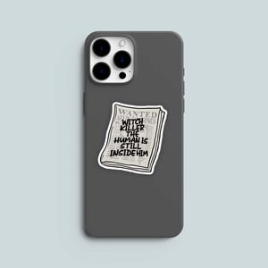 May include: A gray phone case with a sticker of a newspaper headline that reads "WANTED WITCH KILLER THE HUMAN IS STILL INSIDE HIM".