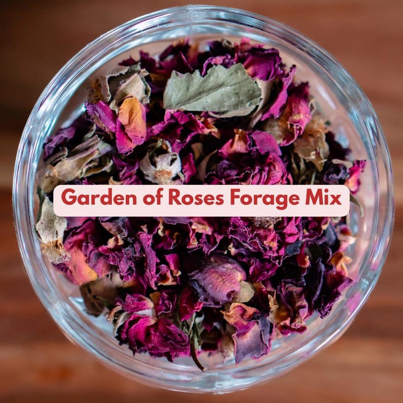 May include: A clear glass bowl filled with dried rose petals and leaves. The petals are various shades of pink and purple, with some tan and green leaves. Text on a pink banner reads "Garden of Roses Forage Mix."