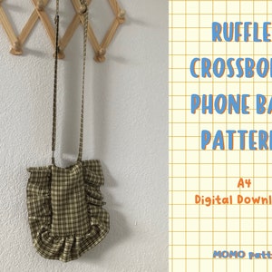 May include: A plaid ruffle crossbody phone bag pattern. The bag is made of fabric with a tan, black, and white checkered pattern. The bag has a long strap and a ruffled edge. The text on the image says "RUFFLE CROSSBODY PHONE BAG PATTERN A4 Digital Download".