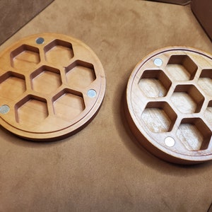 Puede incluir: Dos bandejas redondas de madera con compartimentos hexagonales. Las bandejas son de madera marrón claro y tienen un acabado natural. Cada bandeja tiene siete compartimentos.