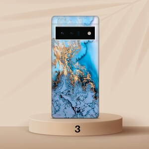 May include: A blue and gold marble phone case with a camera cutout. The case is on a light brown pedestal with the number 3 printed on it.