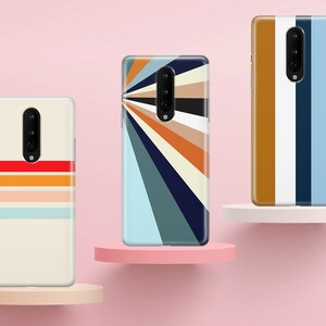 K&ouml;nnte beinhalten: Drei Handyh&uuml;llen mit verschiedenen geometrischen Mustern. Die erste H&uuml;lle hat einen wei&szlig;en Hintergrund mit horizontalen Streifen in Rot, Orange und Blau. Die zweite H&uuml;lle hat einen blauen Hintergrund mit einem strahlenf&ouml;rmigen Muster aus Streifen in Orange, Gelb und Wei&szlig;. Die dritte H&uuml;lle hat einen wei&szlig;en Hintergrund mit vertikalen Streifen in Braun, Wei&szlig; und Blau.