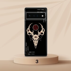 Może przedstawiać: Czarne etui na telefon z wzorem białej czaszki jelenia i poroża. Czaszka ma czerwony pentagram i jedno oko w środku. Tło jest czarne z białym geometrycznym wzorem.