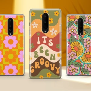 May include: Three phone cases with different retro designs. The first case has a pink and orange floral pattern. The second case has a brown, green, and orange wavy pattern with the text "It's Been Groovy". The third case has a colorful floral pattern with green leaves.