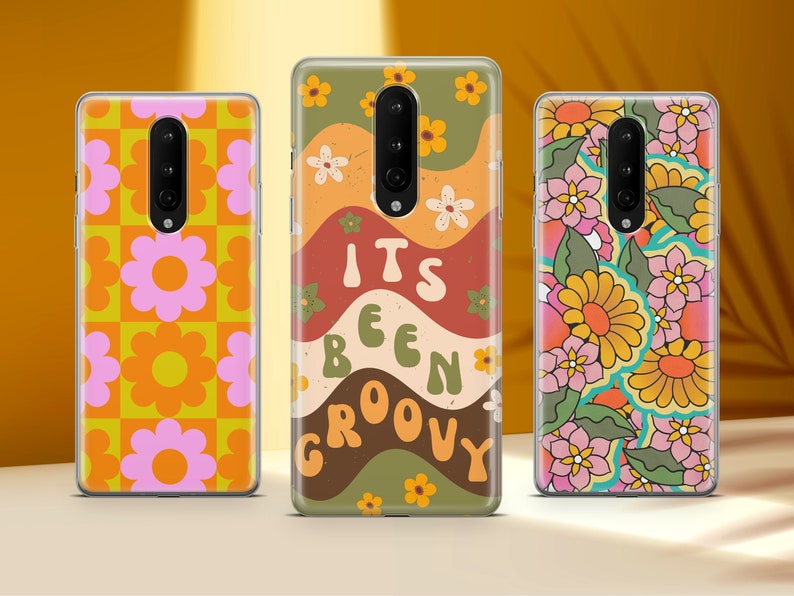 May include: Three phone cases with different retro designs. The first case has a pink and orange floral pattern. The second case has a brown, green, and orange wavy pattern with the text "It's Been Groovy". The third case has a colorful floral pattern with green leaves.