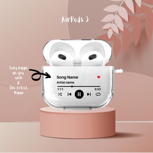 May include: A white AirPods 3 case with a clear back panel. The case has a screen displaying a music player with the text "Song Name" and "Artist name". The screen also shows the time 1:11 and 3:33.
