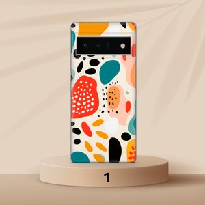 以下が含まれることがあります： カラフルな抽象的なデザインが施された白い携帯電話ケース。デザインには、赤、オレンジ、黄色、緑、青、黒など、さまざまな形と色が含まれています。
