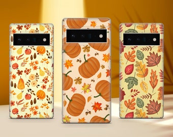 May include: Three phone cases with different autumn-themed designs. The first case features a pattern of pumpkins, leaves, and acorns on a cream background. The second case has a pattern of leaves in shades of orange, yellow, and green on a cream background. The third case has a pattern of pumpkins, leaves, and acorns on a cream background.