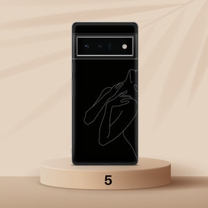 Puede incluir: Una funda de tel&eacute;fono negra con un dibujo de l&iacute;nea blanca de una persona. La funda de tel&eacute;fono est&aacute; en una plataforma beige con el n&uacute;mero 5 impreso en ella.