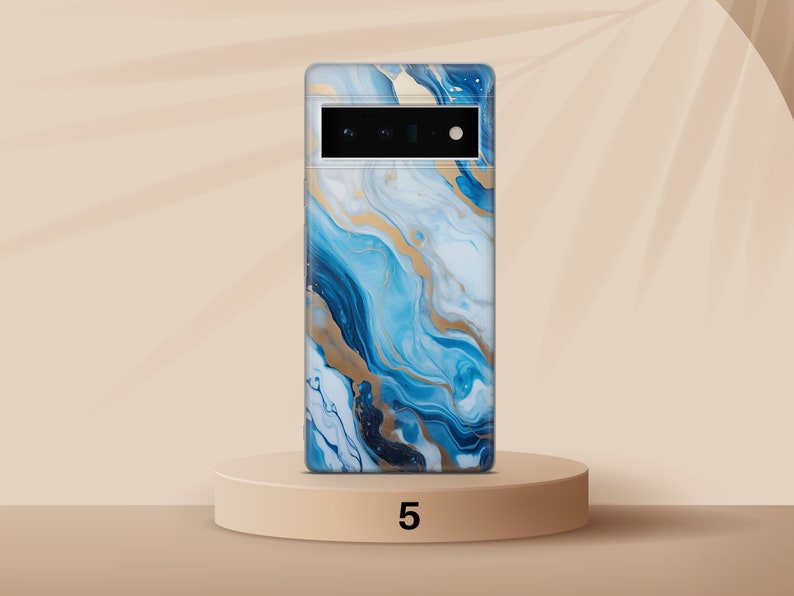 May include: A blue and gold abstract phone case with a camera cutout. The case is on a light brown pedestal.