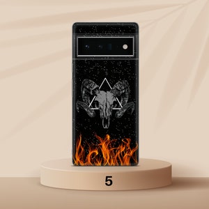 Może przedstawiać: Czarne etui na telefon z grafiką przedstawiającą czaszkę barana i płomienie. Czaszka znajduje się w tr&oacute;jkącie, a płomienie u dołu etui.