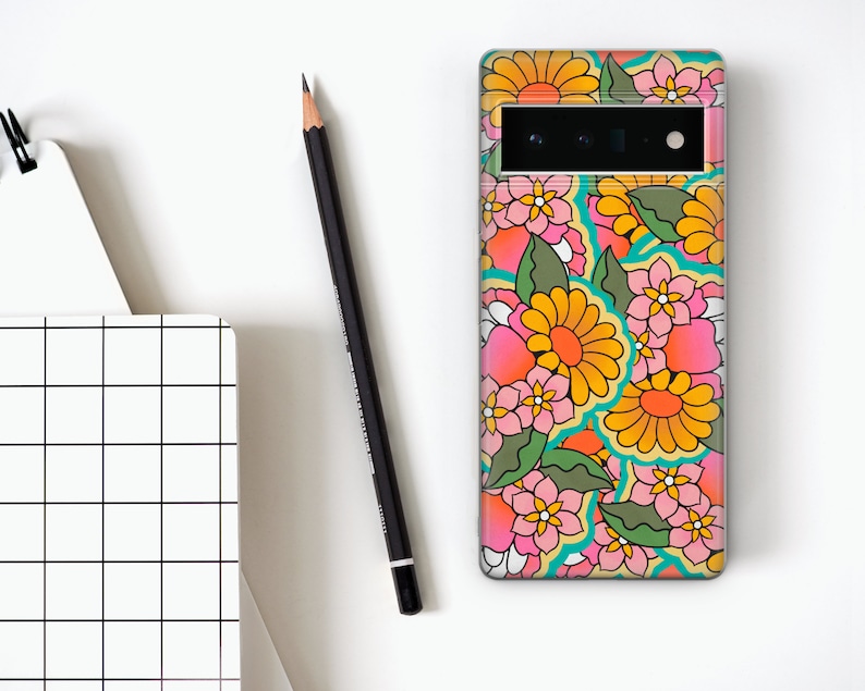 May include: A phone case with a colorful floral pattern. The flowers are pink, yellow, and orange with green leaves. The case has a cutout for the camera lens.