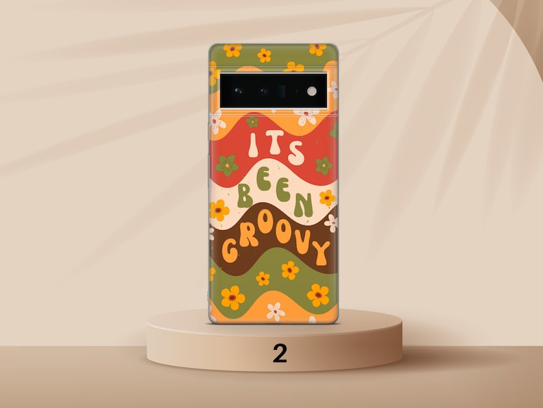 May include: A phone case with a retro design featuring wavy lines in shades of orange, red, green, and brown. The case has a floral pattern and the text "It's Been Groovy".